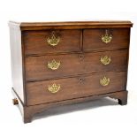 A George III oak chest of two short and two long drawers with pierced brass drop handles,
