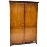 A Kendal Milne reproduction two-door wardrobe with a dentil moulded cornice above a pair of