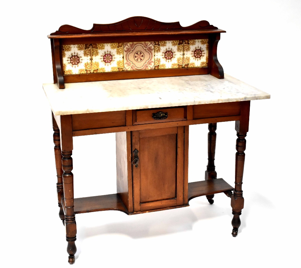 An Edwardian mahogany wash stand with marble top and tiled gallery above a base with cupboard and