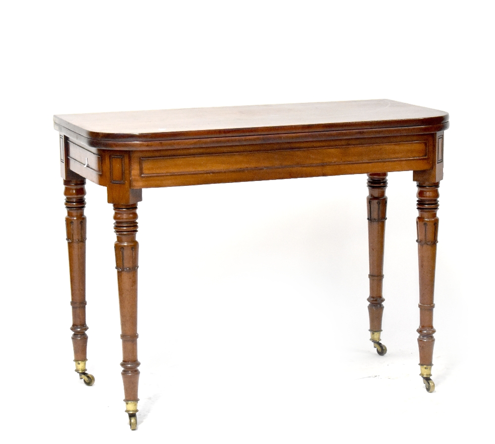 A William IV mahogany fold-over tea table supported on carved and turned tapering legs with brass