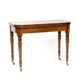 A William IV mahogany fold-over tea table supported on carved and turned tapering legs with brass