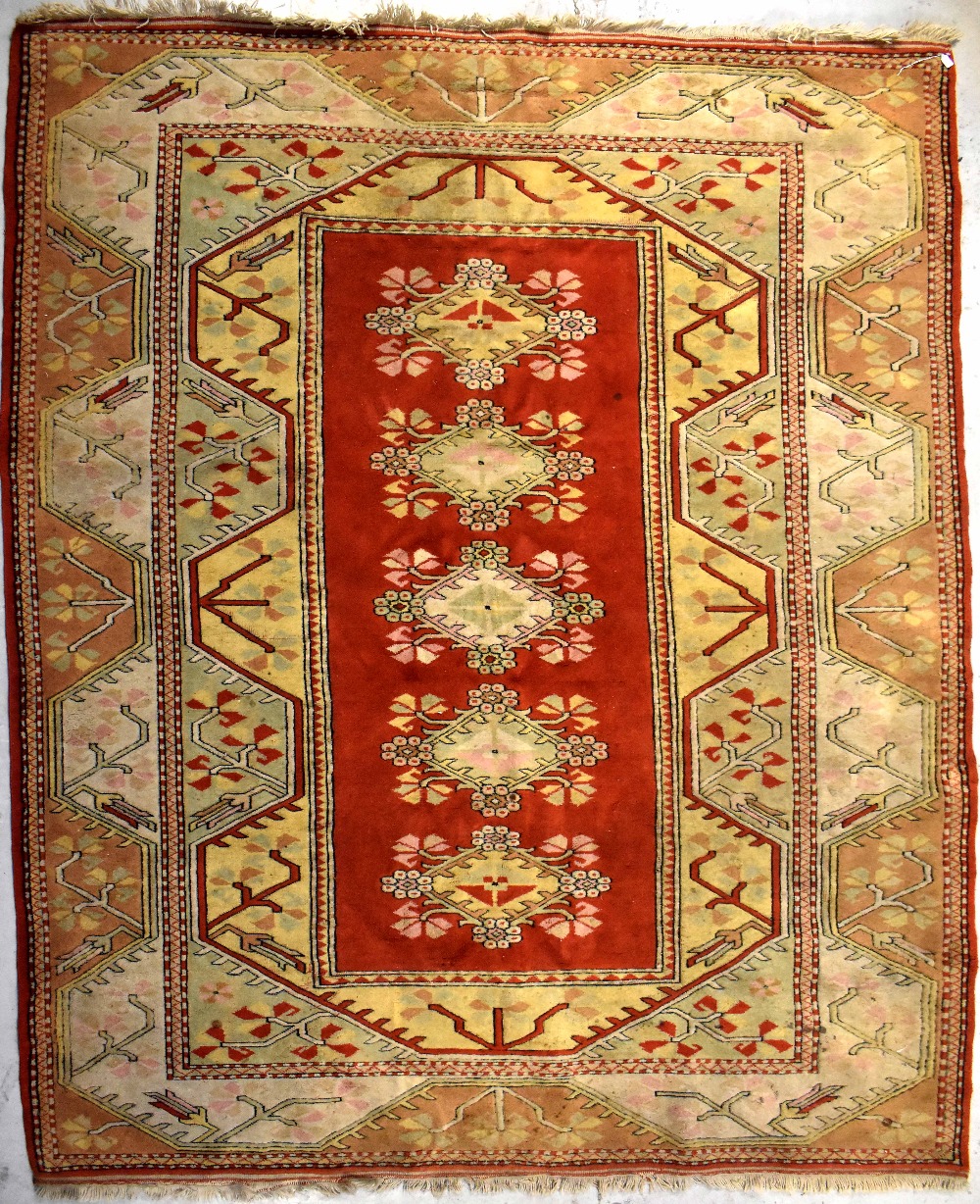 A Caucasian wool rug with rectangular central panel of five stylised floral medallions within