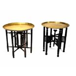 Two Benares brass circular tray-top tables with engraved decoration on ebonised folding bases,