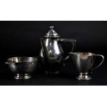 A cased George V hallmarked silver three-piece service comprising Arts & Crafts style tea pot,