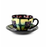 A Moorcroft cup and saucer, pistachio and dark green ground with violet pattern,