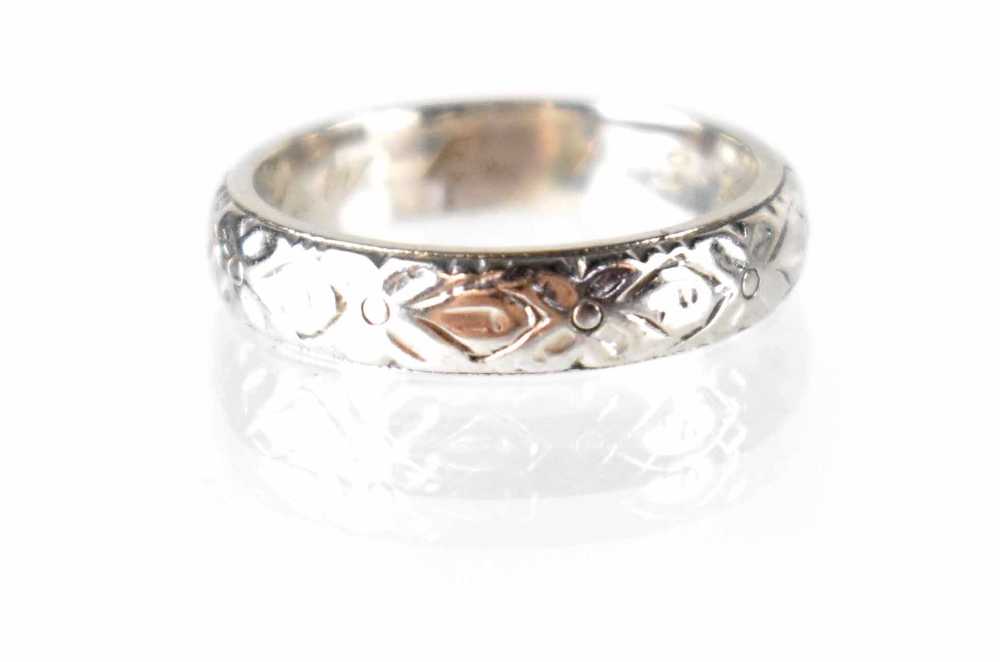 An 18ct white gold band ring with a repeating rose head pattern,