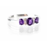 A 9ct white gold three stone amethyst and diamond ring,