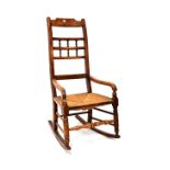 A 19th century rush-seated rocking chair with bobbin turned rail back and open arms,