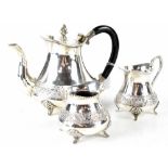 A white metal three-piece tea service comprising teapot, milk jug and sugar bowl,
