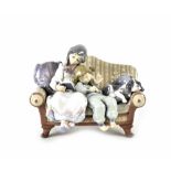 A Lladró figure group of children and dog on sofa, 21cm.