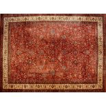 A Keshan wool carpet with scrolling floral motifs on a burgundy ground within floral multi-borders,