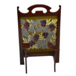 An Arts & Crafts firescreen with shaped uprights and grape and vine embroidered panel, numbered