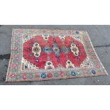 A large hand knotted woollen carpet with geometric designs on a red ground within a multi-border,