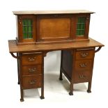 An Arts & Crafts oak desk, the fall front flanked by a pair of leaded glazed doors above base fitted