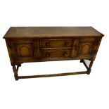 A reproduction oak sideboard, the rectangular top above two central drawers flanked by panel doors