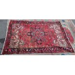 A large hand knotted Persian carpet, with elaborate geometric designs on a red ground within a