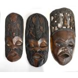 Three large African carved tribal masks including a lignum vitae example with pierced figural detail