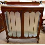 A reproduction bowfront two door display cabinet with twin glazed doors enclosing glass shelves on