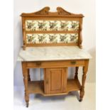 A late Victorian satin walnut washstand with floral decorated tiled back, white marble top and