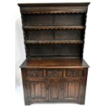 A reproduction oak dresser, the boarded plate rack above a base of three frieze drawers and twin