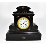 A late 19th century black slate eight day mantel clock of architectural form, the enamelled dial set