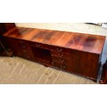 A very large reproduction mahogany sideboard with an arrangement of drawers and cupboard doors,