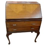A reproduction bureau, the fall front enclosing fitted interior above two drawers on cabriole