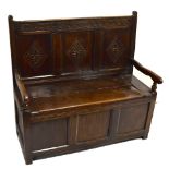 A late Victorian carved oak box seat settle, with carved triple panel back and hinged storage