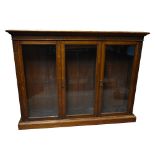 A late 19th century oak bookcase three glazed doors enclosing adjustable shelves, on plinth base,