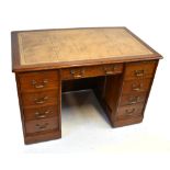 An early 20th century oak nine drawer pedestal desk with gilt tooled leather top, width 121cm, depth