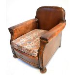 An early 20th century leather club chair on oak bun feet.Additional InformationHeavy wear as