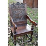 A large 19th century carved oak Wainscot chair with carved panel back and open arms, solid seat
