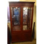 A reproduction mahogany display cabinet, the moulded cornice above twin glazed doors enclosing