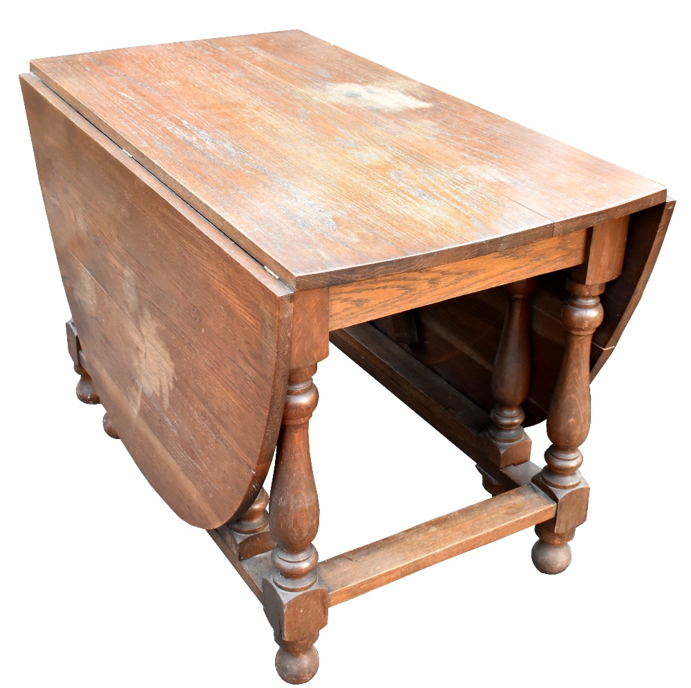 A large oak oval drop leaf dining table on gateleg supports, width 115cm.