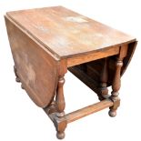 A large oak oval drop leaf dining table on gateleg supports, width 115cm.