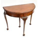 An early 20th century mahogany demi-lune foldover games table on carved cabriole supports to ball