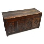 An 18th century oak coffer, the hinged lid above a lozenge carved four-panel front, width 129cm,