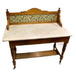 An Edwardian oak washstand with ceramic tiled back, white marble top and base of two drawers