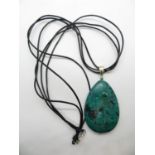 Large green malachite stone with silver fixings on black leather thong