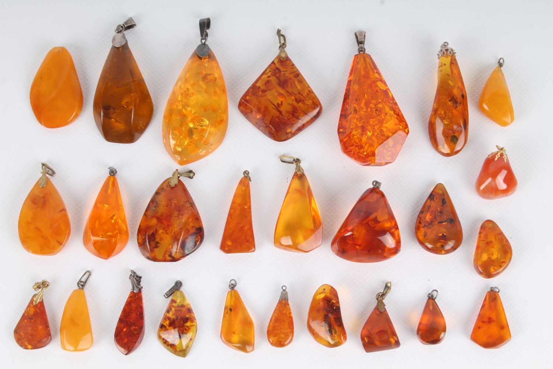 26 Bernstein Anhänger, teils mit Silber, 26 amber pendants, partly in silver,