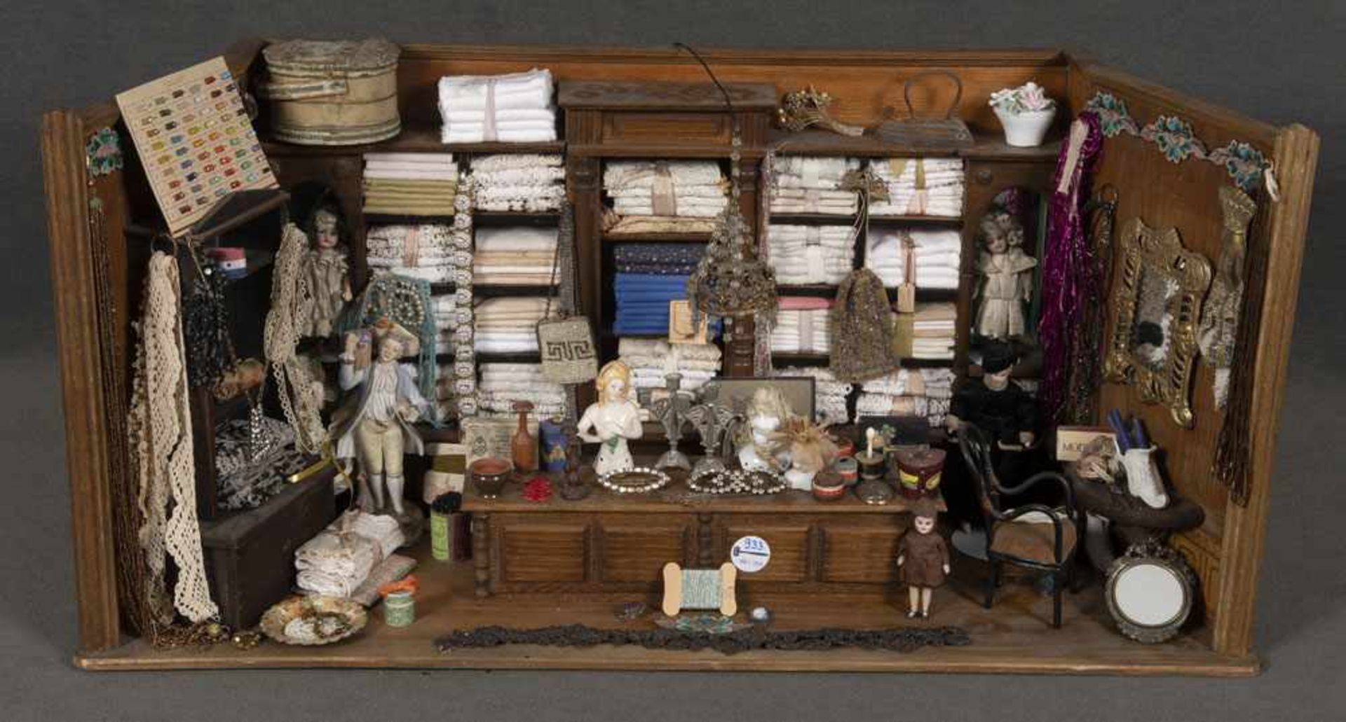 Puppenstuben-Kaufladen für Kurzwaren. Deutsch um 1900. Mit Holztheke und Regalen, reich bestückt mit