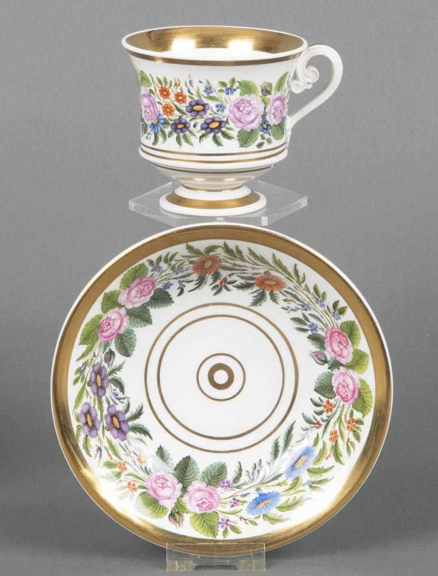 Tasse mit Unterschale. Nymphenburg 1830. Beide Teile bunt bemalt mit Floralbordüren, breite