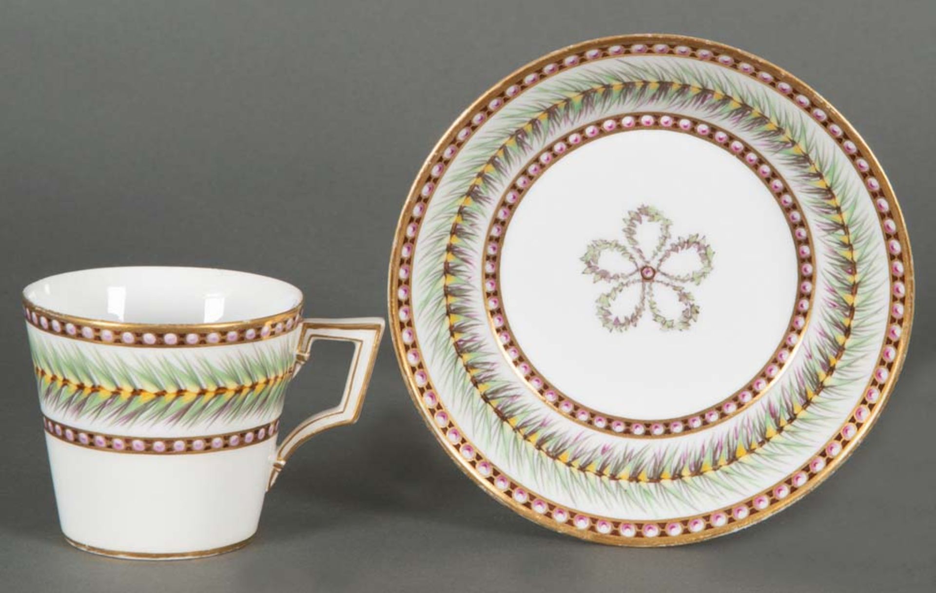 Tasse mit Unterschale Konisch. Berlin um 1800. Porzellan, bunt bemalt mit Blattbordüren, Goldra