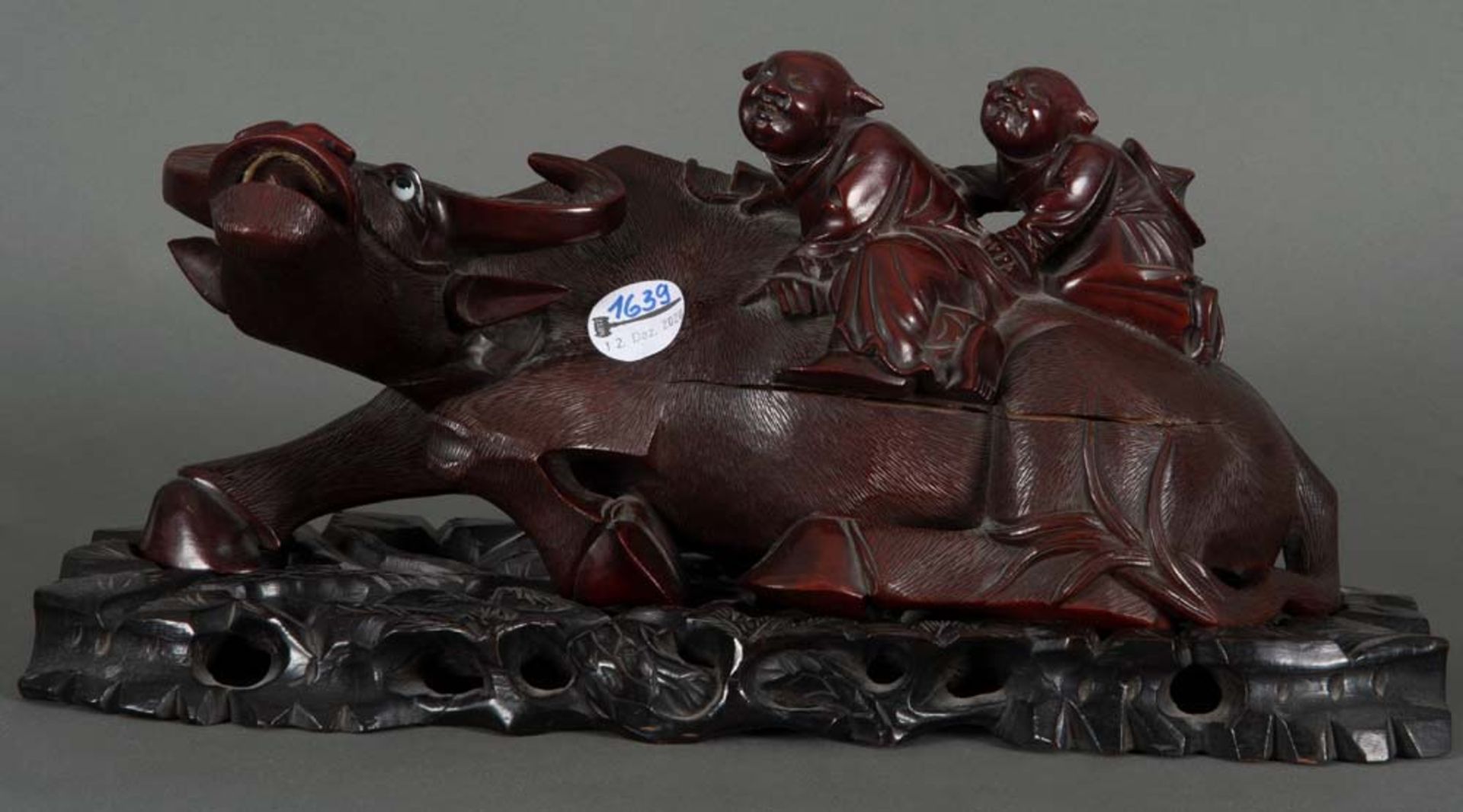 Büffel mit zwei Reitern, auf Sockel. Asien. Hartholz, geschnitzt, mit Beinzähnen und Glasaugen, H=