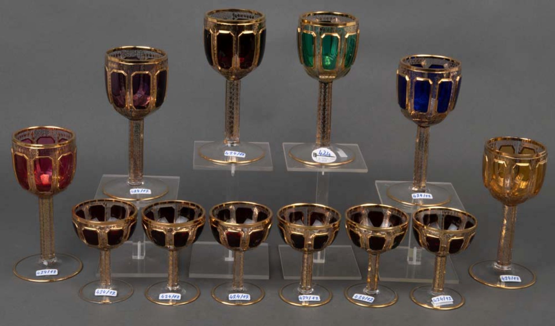 Zwölf Trinkgläser. Wohl Böhmen 20. Jh. Farbiges Glas, gold gehöht, H=10,5 bis 17,5 cm.