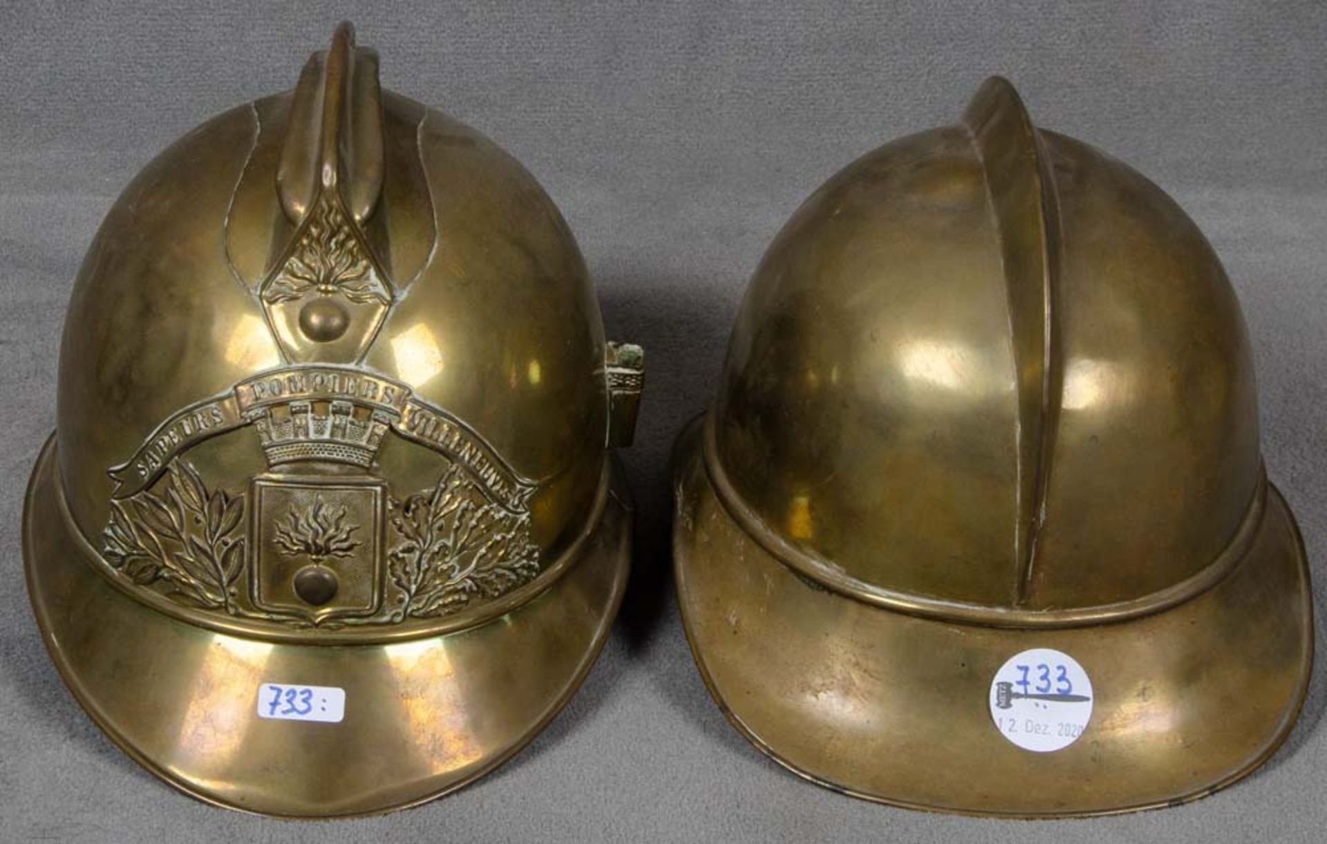 Zwei Feuerwehrhelme. Frankreich / Deutschland um 1900. Messing, mit Originalfutter und Kinnriemen.