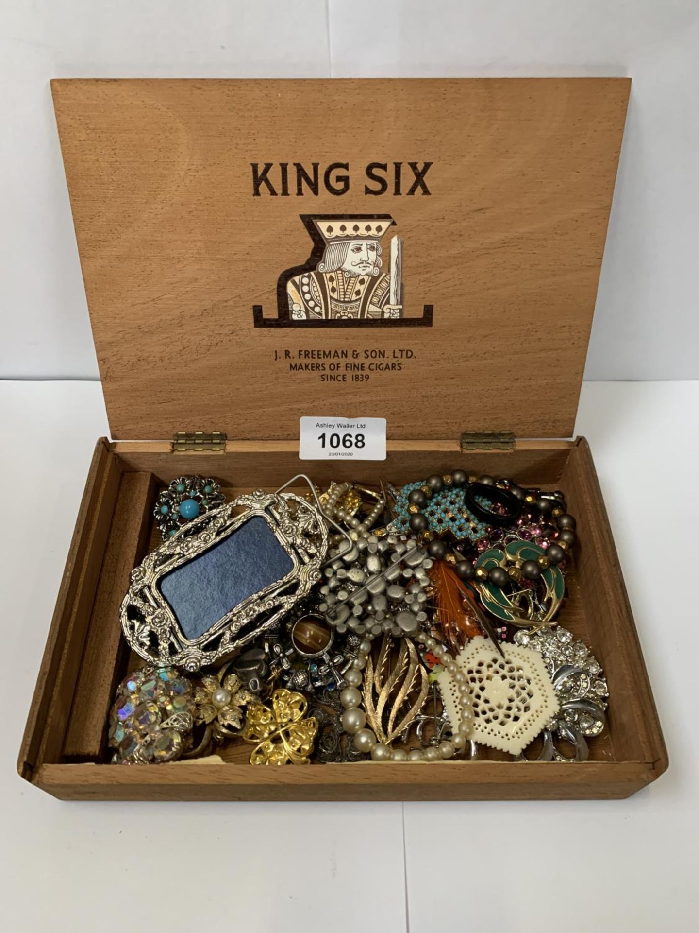 A WOODEN BOX OF ASSORTED BROOCHES