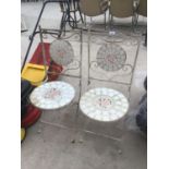 A PAIR OF FOLDING METAL ORNATE BISTRO STYLE CHAIRS WITH ROSE DESIGN TILED SEATS AND BACKS