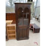 A PRIORY STYLE OAK CORNER CUPBOARD WITH LOWER LINEN FOLD DOOR AND UPPER GLAZED PANEL DOOR