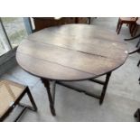 A GEORGIAN CIRCULAR DROP LEAF OAK DINING TABLE ON TURNED SUPPORTS